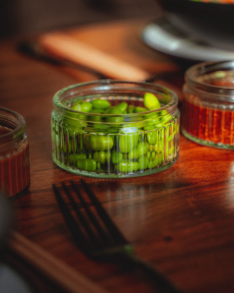 A ramekin bowl full of edamame on a table, as an easy and healthy snack option.