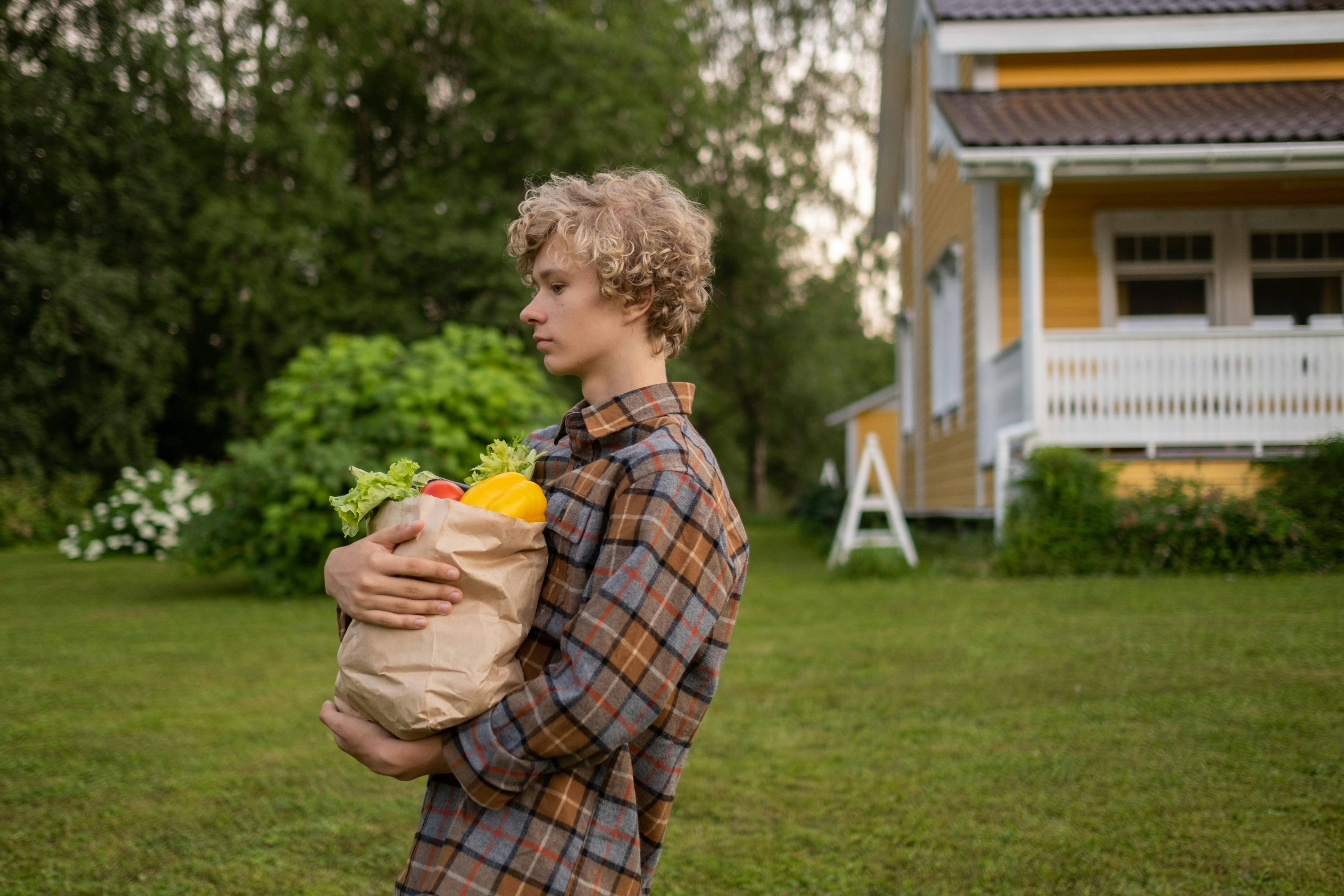 A person with curly hair and plaid shirt carries an armful of groceries as an analogy for cognitive overhead.