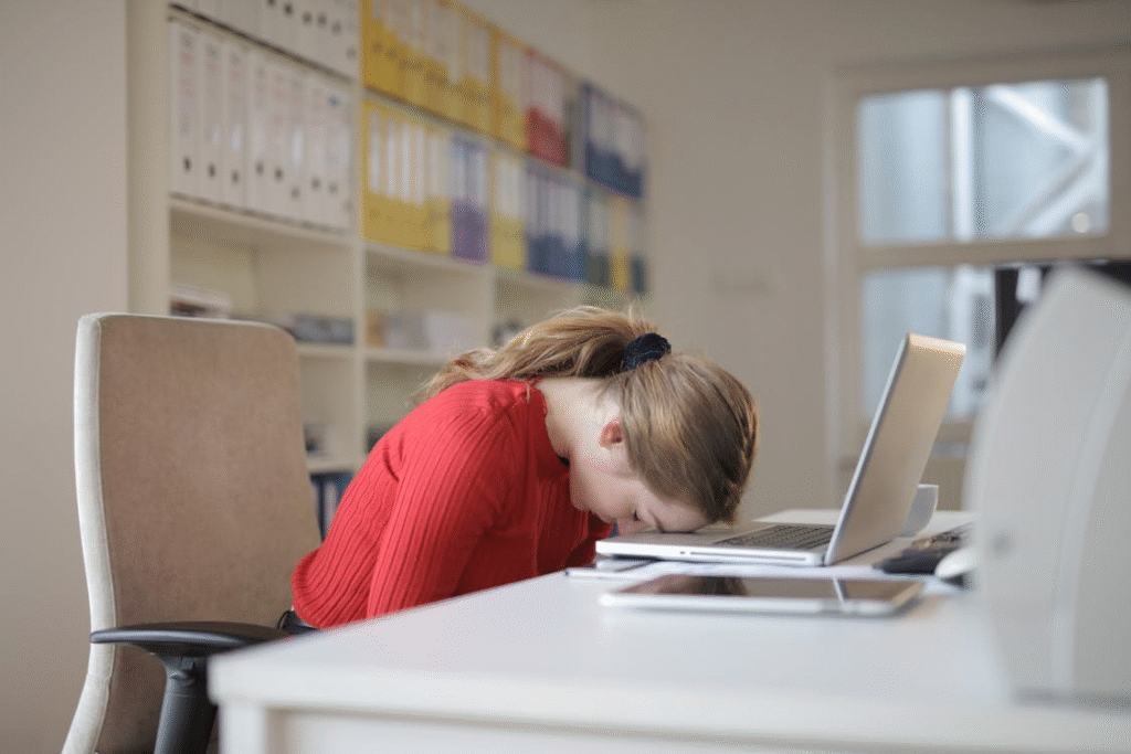 A woman sits at her computer laying her head on the keyboard, experiencing stress caused by executive dysfunction.