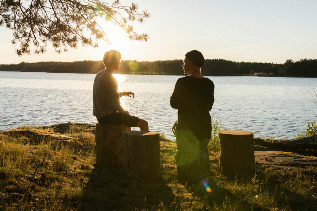 Two friends talking outside in front of a lake, taking care of their mental health.